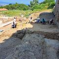 Students digging next to a large wall