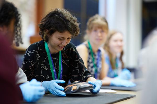 A smiling woman handling ancient pottery