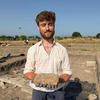 Adam Paterson n a dig holding an item he has excavated